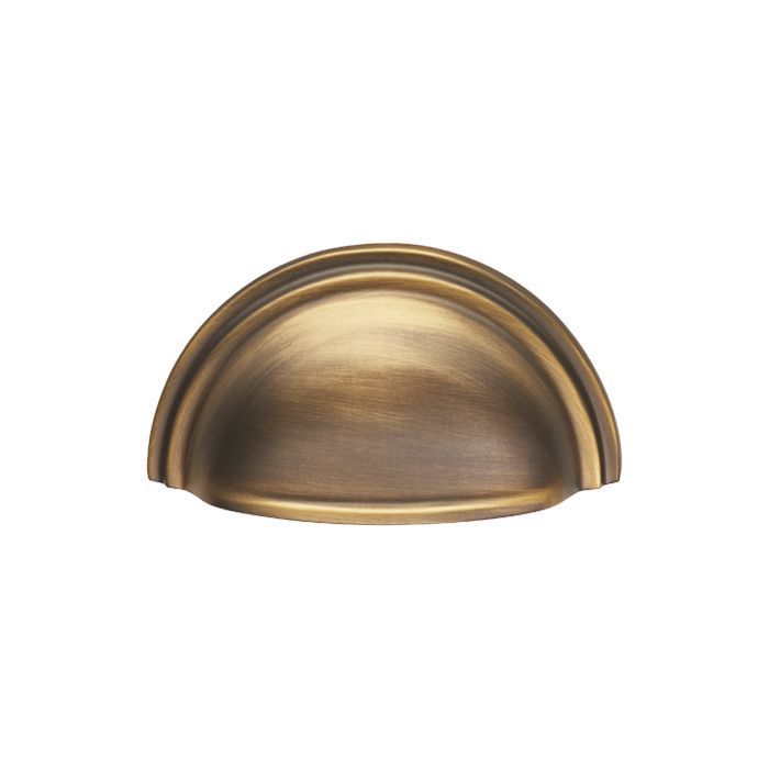 A classic Victorian cup pull handle in antique brass for kitchen drawers.